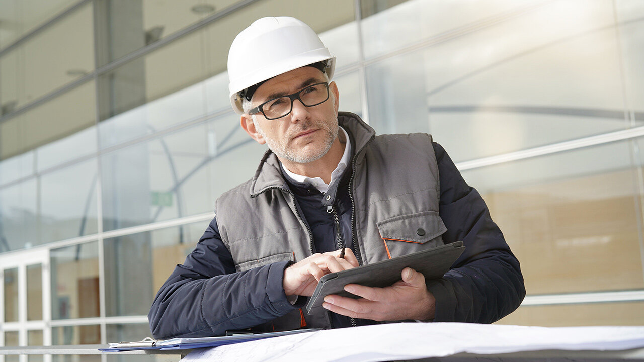 Homme avec un casque de chantier utilisant une tablette